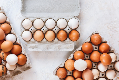 Fresh white and brown hen's eggs in eco cardboard  tray on kitchen wood  countertop photo