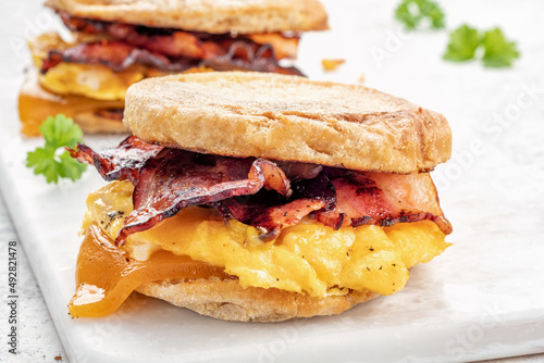 English muffin, egg, ham, and cheese breakfast sandwich on a cutting board