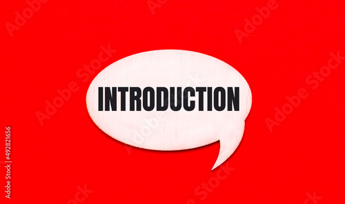 On a bright red background, a light wooden curly card with the text INTRODUCTION