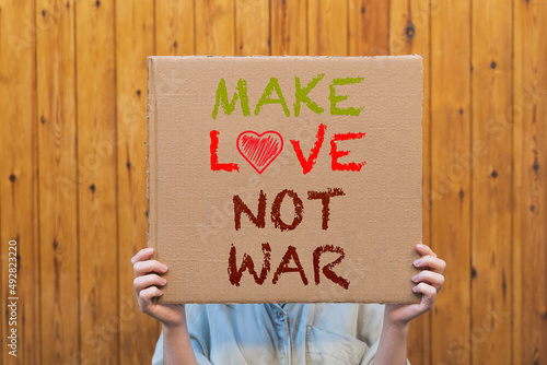 Unrecognizable woman holding a sign in favor of love and against war. Concept of peace and love