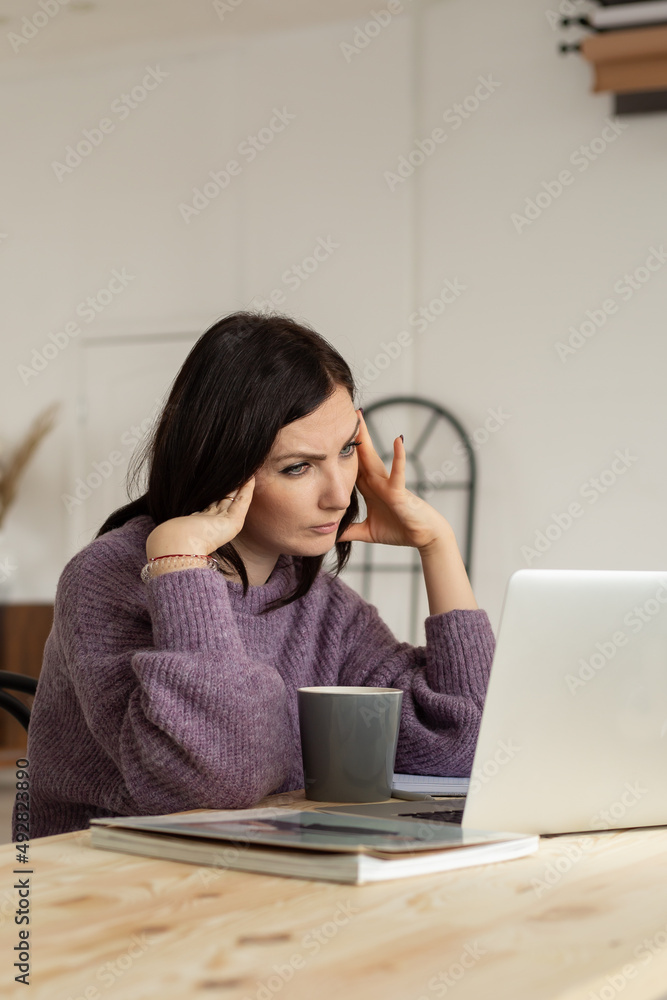 a cute brunette girl in a lilac sweater is working on a laptop, looking at the screen and thinking, a light background a cute brunette girl in a lilac sweater is working on a laptop, looking at the screen and thinking, a light background