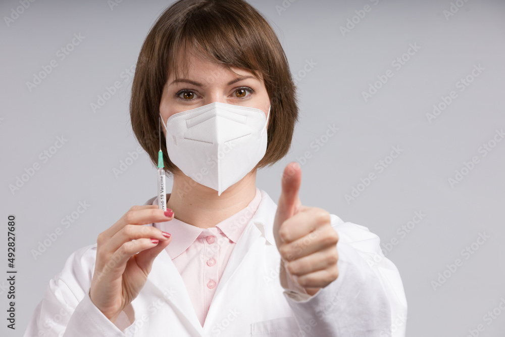 female doctor or nurse with syringe pulled up with a vaccination serum shows thumbs up
