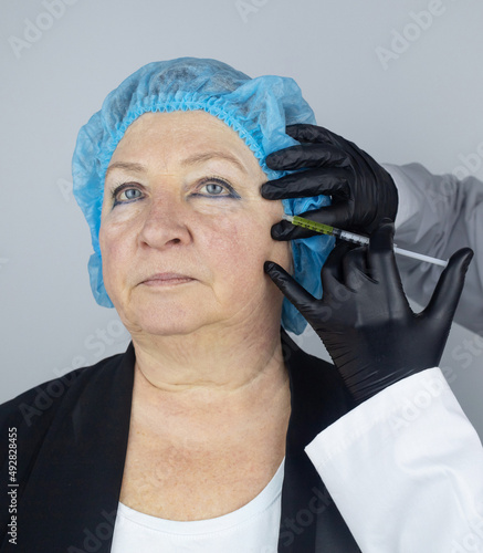 Botulinum toxin injection. Senior woman at the appointment with a beautician who is preparing to give anti-wrinkle injections. Loose skin and hypotension. Mimic wrinkles and contouring photo