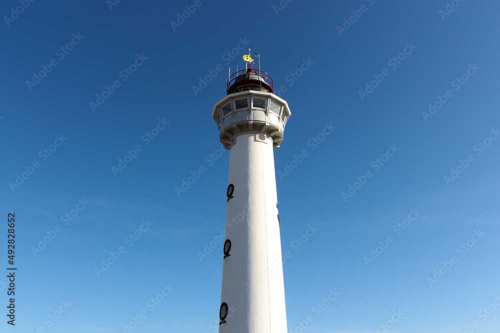 White lighthouse with blue sky on background.