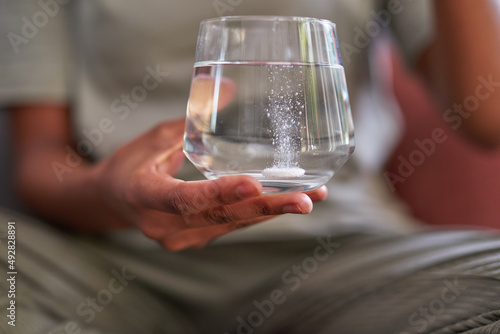 Photos A close up of a fizzy effervescent tablet in a glass of water for flu treatment
