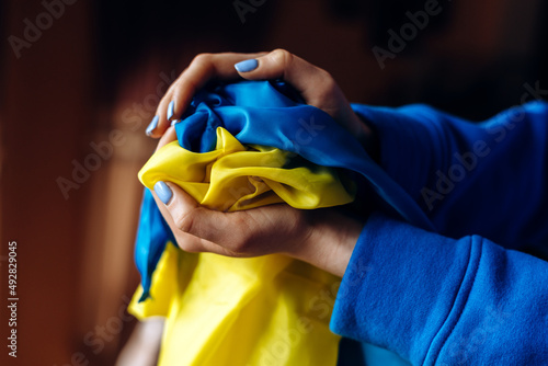 Yellow-blue flag of Ukraine is at the hands of the woman with nails painted at the blue and yellow