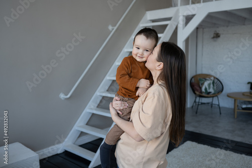 A happy son in the arms of his mother, in the interior of the apartment. © Lys Owl