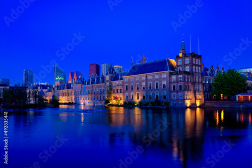 View of the Binnenhof House of Parliament and the Hofvijver lake with downtown skyscrapers in background illuminated in the evening. The Hague  Netherlands