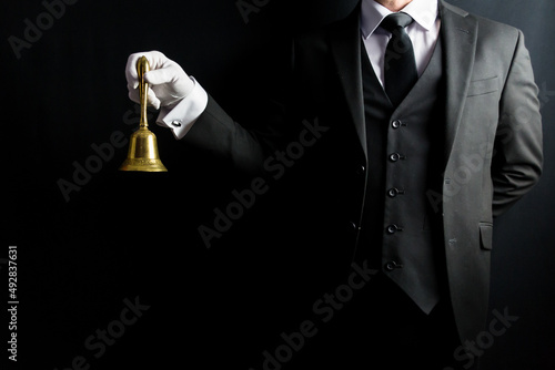 Tableau sur toile Portrait of Butler in Dark Formal Suit and White Gloves Holding Gold Bell