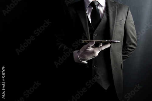 Portrait of Formal Butler or Waiter in Dark Suit and White Gloves Holding Silver Serving Tray. Professional Hospitality and Courtesy.