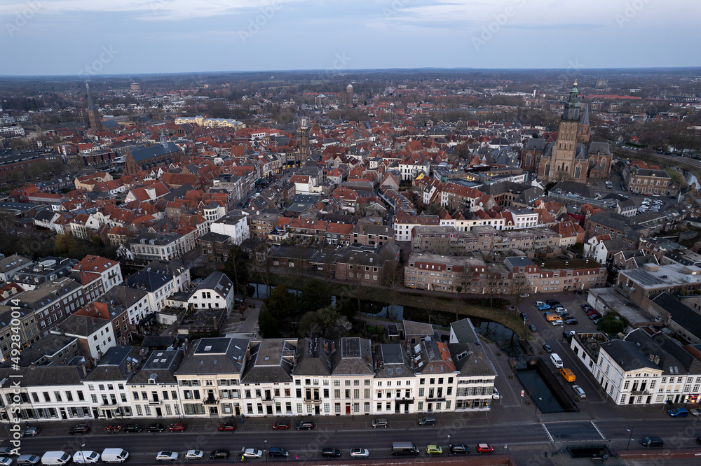 Obraz premium Aerial countenance view of Zutphen, The Netherlands, during sunset with magenta glow on the horizon in the background and high water level in the foreground in front of typical white facades
