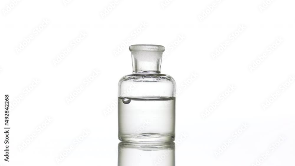Drop falling into old fashioned bottle with clear liquid Drop falling into old fashioned bottle with clear liquid