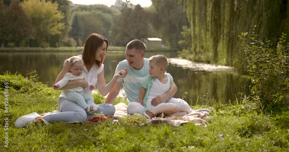 Young family with two children outdoors by the river on summer picnic Young family with two children outdoors by the river on summer picnic
