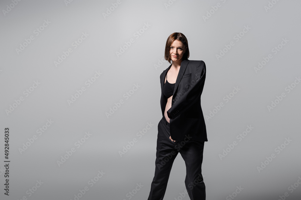 Brunette pregnant woman in jacket looking at camera isolated on grey Brunette pregnant woman in jacket looking at camera isolated on grey