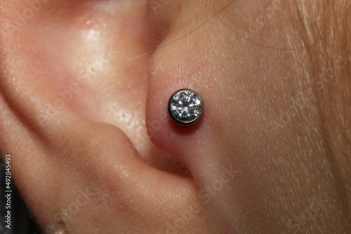 Girl ear piercing. Macro.
Tragus piercing + titanium labret with cubic zirconia. photo