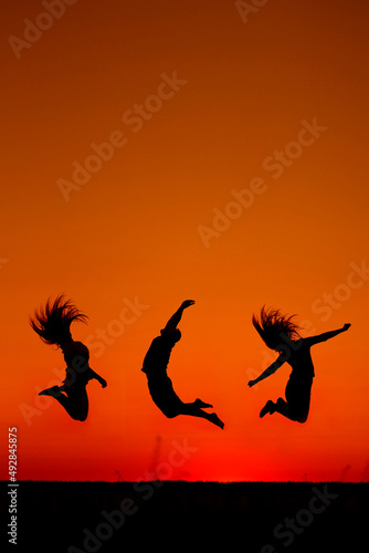 silhouette of three people jumped into the sunrise