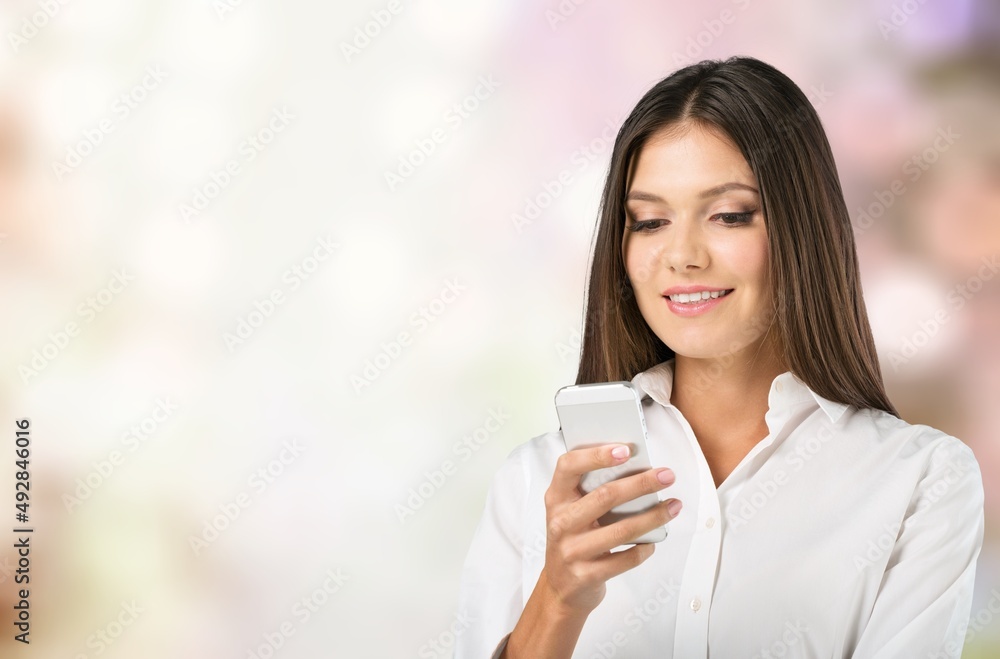 Photo of smiling woman looks with happy expression uses mobile phone for chatting online Photo of smiling woman looks with happy expression uses mobile phone for chatting online