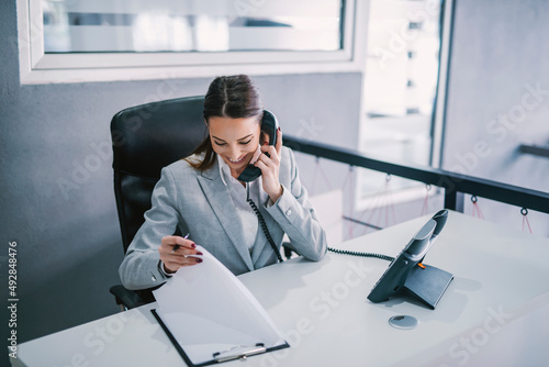 An assistant schedules a meeting on the phone at modern office. photo