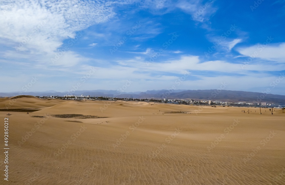 Hoteles y Resorts en la distancia detrás de las dunas costeras de la playa de Maspalomas, isla de Gran Canaria, España. Paisaje desértico y costero diseñado por el efecto del viento sobre la arena.