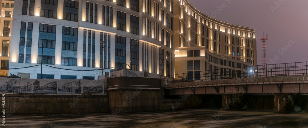 A business center under construction in the city at night. Business architecture. Brightly lit windows in a new building.