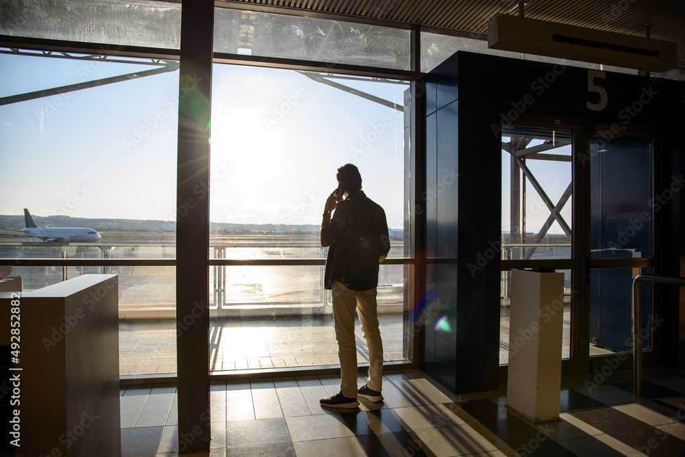 Fototapeta premium Man talking on the phone in the departure lounge while waiting for his flight