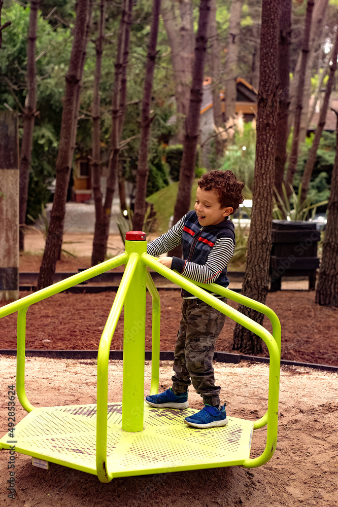 photo of child having fun on spinning game in the park