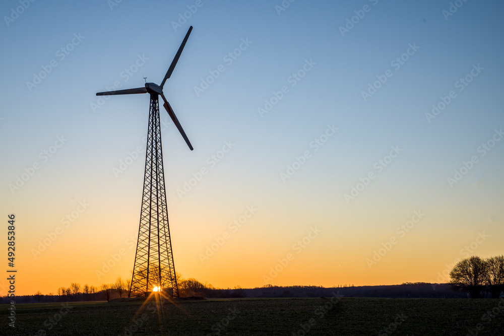 ein Windkraftrad am Morgen auf einem Feld bei Sonnenaufgang ein Windkraftrad am Morgen auf einem Feld bei Sonnenaufgang