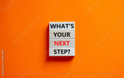 What is your next step symbol. Concept words What is your next step on wooden blocks. Beautiful orange table orange background. What is your next step business concept. Copy space.