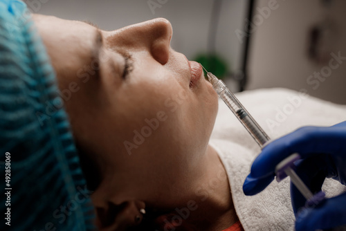 A cosmetologist injects a syringe into a patient