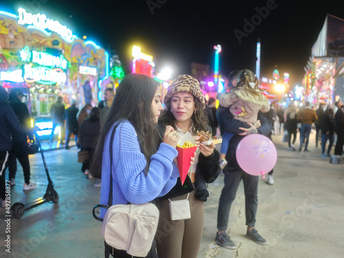 Two friends talking whie eating fast food during a night fair