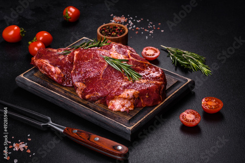 Raw organic marbled beef steaks with spices on a wooden cutting board
