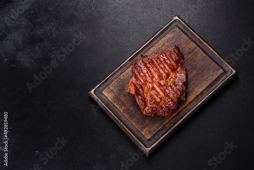 Grilled ribeye beef steak, herbs and spices on a dark table