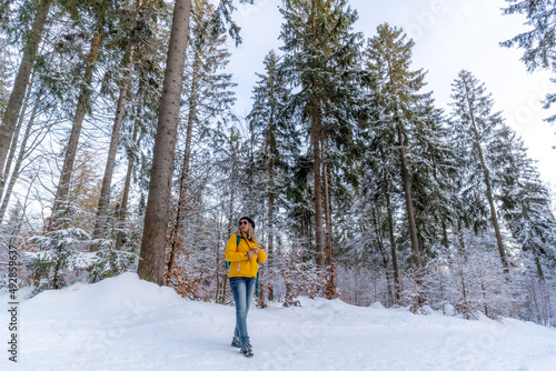 Winterwandern  im Winterwald 
Frau mit gelber Jacke und Rucksack