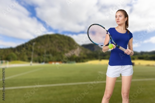 Cheerful sportswoman smiling aside, holding tennis racket ready for playing tennis in the city © BillionPhotos.com