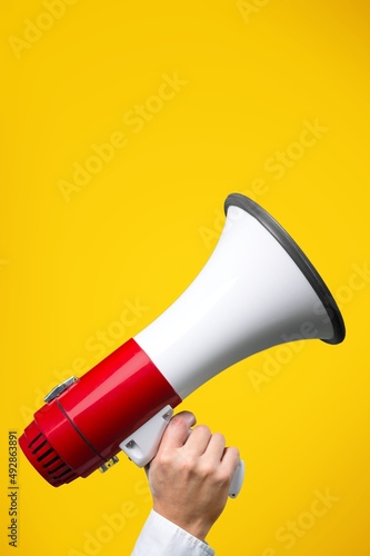 Megaphone in woman hands on color background.