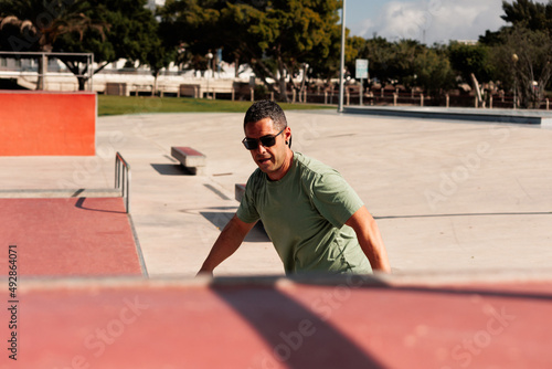 Man riding skateboard in urban street skatepark. Casual guy wearing shorts and T-shirt.