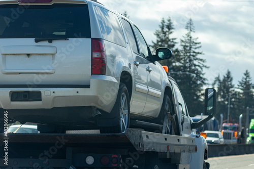 white suv vehicle on tow truck lifted for transportation