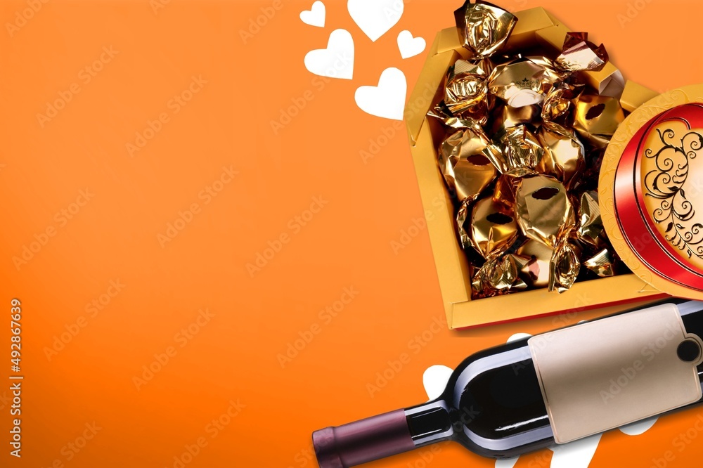 Bottle of wine on colored background for Valentine Day with gift and chocolate.