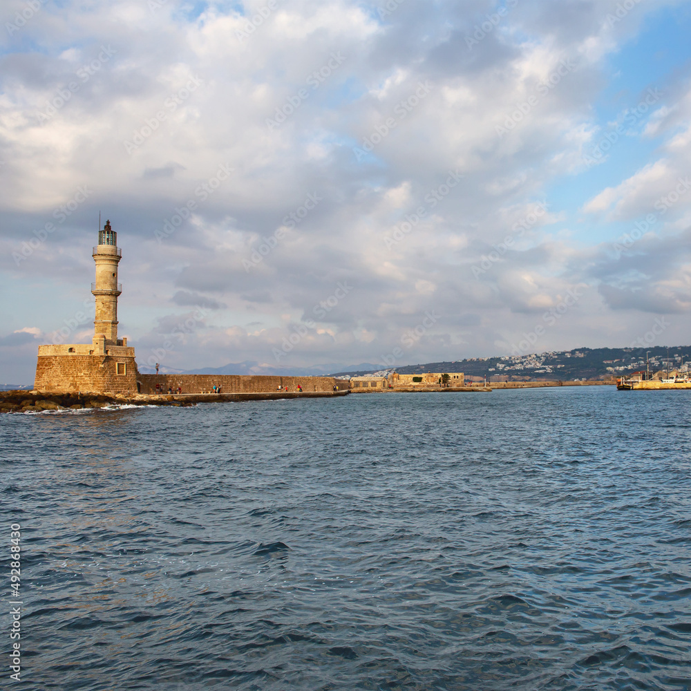 view from the sea to the old stone lighthouse in the small Greek resort town of Rethymno