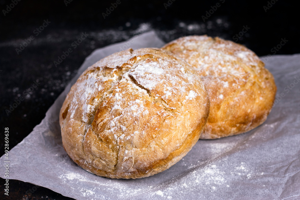 Fresh homemade crisp bread. Healthy baked bread on Kraft paper over black rustic wooden table.