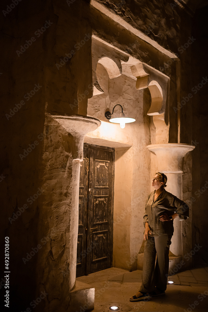 Fototapeta premium Woman tourist walking in Al Seef Meraas Dubai - old historical district with traditional Arabic architecture