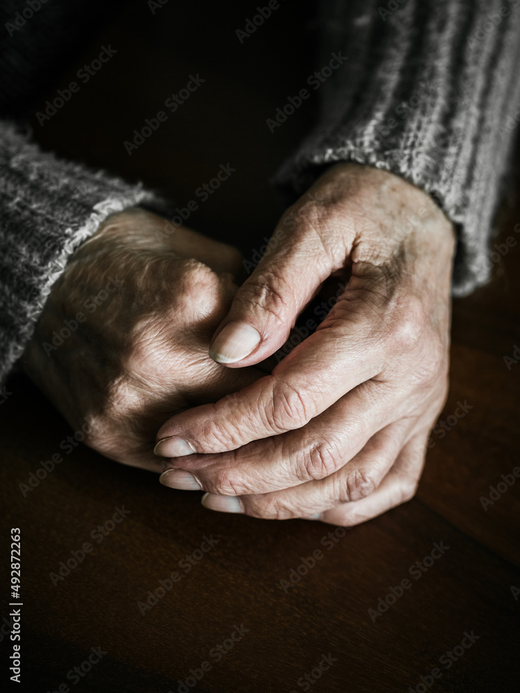 Close up of senior woman hands on table. Dramatic photography