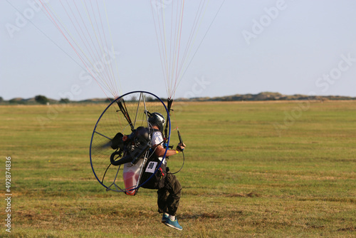 Paramotor pilot taking off from a field 