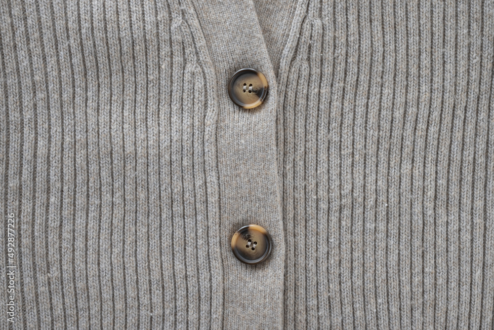 Gray cozy sweater with brown buttons is knitted from natural wool texture, close-up. Gray cozy sweater with brown buttons is knitted from natural wool texture, close-up.