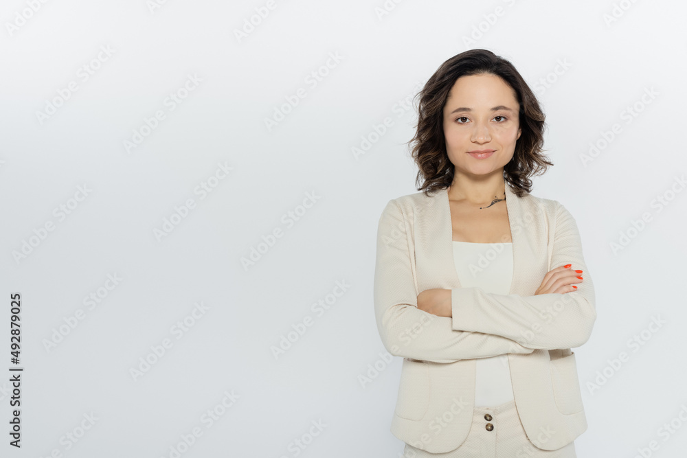 Brunette businesswoman in formal wear crossing arms isolated on grey, feminism concept. Brunette businesswoman in formal wear crossing arms isolated on grey, feminism concept.