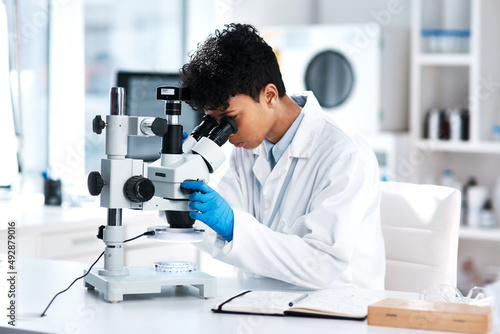 Theres a lot to discover about the world around us. Shot of a young scientist using a microscope in a lab.