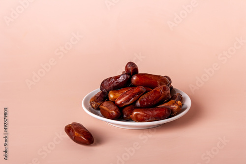 dates in a plate on a beige background, copy space