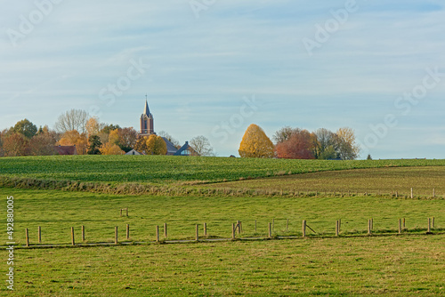 Farmland with church qnd bqre trees in the flemish countryside. Onkerzele, belgium