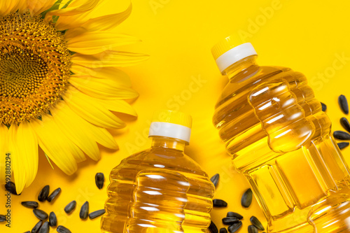 Obraz na plátně Plastic bottles with sunflower oil, fresh yellow sunflowers, sunflower seeds on yellow background