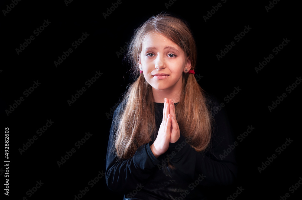 Young pretty girl with request, emotions of sadness and pride prays at the same time on a dark background. The girl prays for peace for her country - Ukraine Young pretty girl with request, emotions of sadness and pride prays at the same time on a dark background. The girl prays for peace for her country - Ukraine